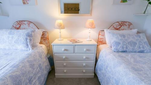 a bedroom with two beds and a nightstand with two lamps at Aber in Moelfre