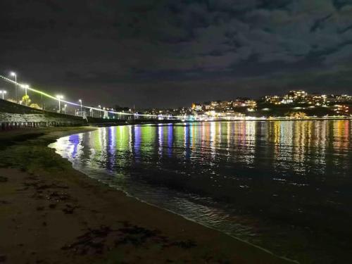 a beach at night with lights on the water at Lovely Two Bedroom Apartment, with private garden! in Torquay