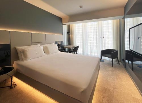 a bedroom with a large white bed and a desk at Oca Bom Sucesso Hotel in Porto