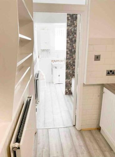 a hallway of a kitchen with a white floor at Lovely Two Bedroom Apartment, with private garden! in Torquay