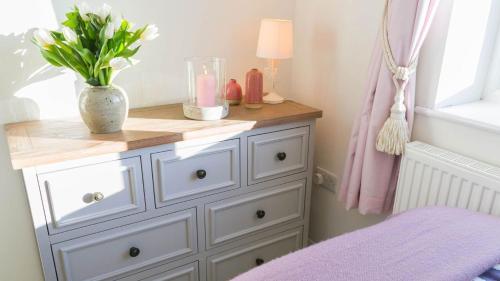 a white dresser with a vase of flowers on it at Bron Heulog in Llanerchymedd