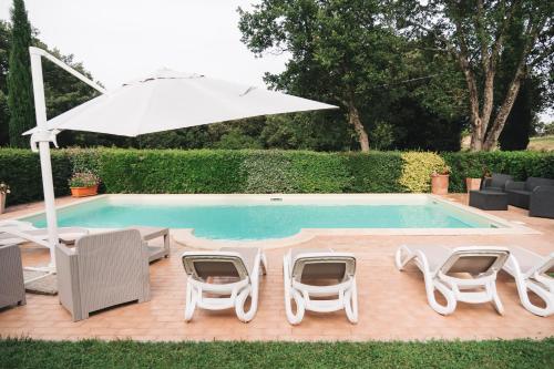 a group of chairs and an umbrella next to a pool at Villa San Giusto - Pool&Relax in Montemassi