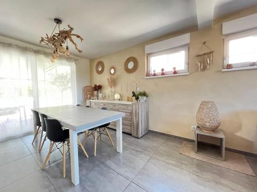 a dining room with a white table and chairs at Maison Coquelicots au calme 10 min de Colmar in Bischwihr