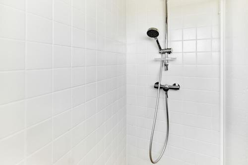 a shower in a white tiled wall with a shower head at SlopeSide apartment in Loučná pod Klínovcem