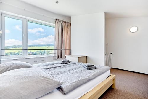 ein Schlafzimmer mit einem großen Bett mit einem großen Fenster in der Unterkunft SlopeSide by Mountain ways in Loučná pod Klínovcem