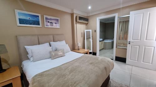 a bedroom with a large white bed and a bathroom at Accommodation Front - Dazzling 4 Sleeper near Ushaka Marine World in Durban