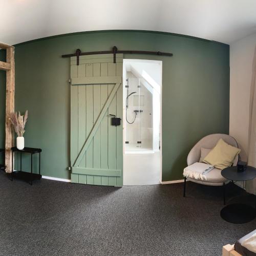 una habitación con una puerta verde y una silla en Landhotel Stöckener Hof en Rethem