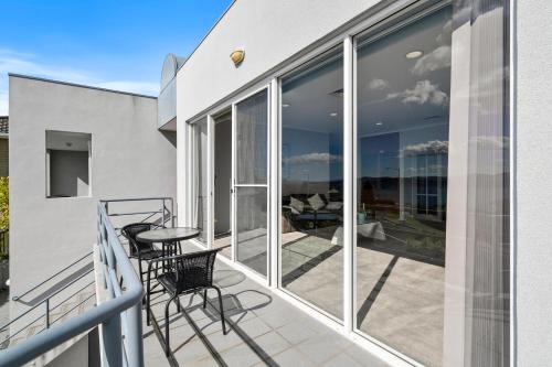 a balcony with glass doors and a table and chairs at Super nice house with sea view free parking in Sandy Bay
