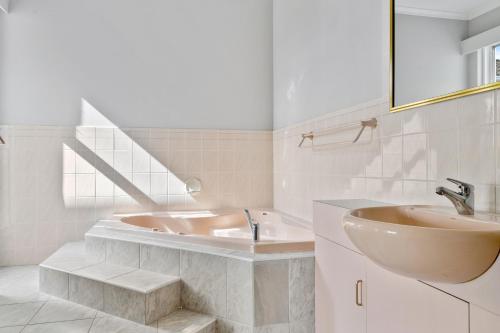 un bagno bianco con vasca e lavandino di Super nice house with sea view free parking a Sandy Bay
