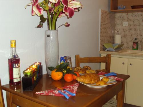 a table with a plate of food and a vase with flowers at Hotel Vasilis Nafplio in Nafplio