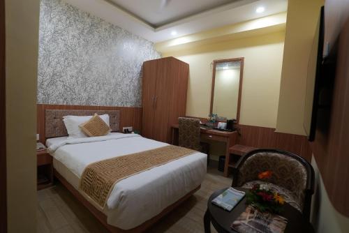 a hotel room with a bed and a table and a chair at The Royal Bihar in Patna