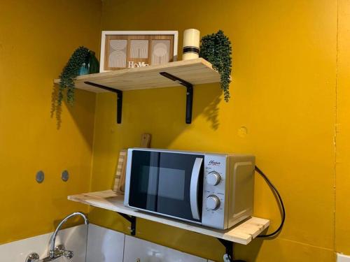 a microwave sitting on a shelf on a yellow wall at Just Vibes at 0953 Maboneng Precinct in Johannesburg