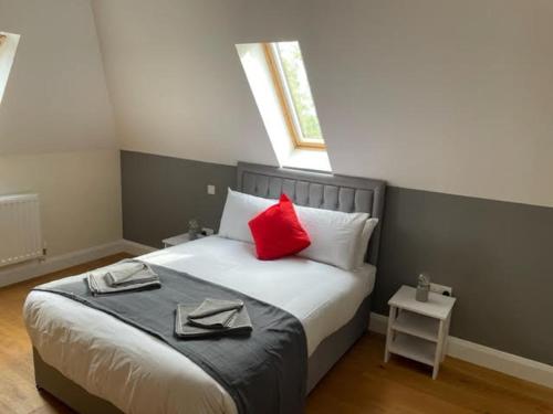 a bedroom with a bed with red pillows and a window at Two Bedroom Duplex Apartment The Priory in St. Ives