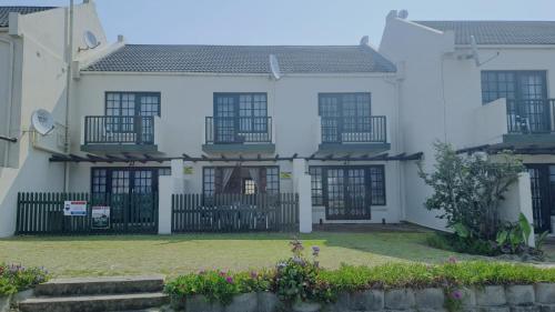 a white house with black windows and a yard at Beachfront at 22 Settler's Sands in Port Alfred