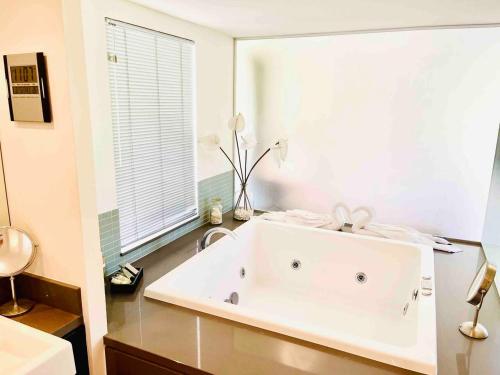 a white bath tub in a bathroom with a window at Paradise Escape - Poolside Ground Floor - Sea Temple Resort and Spa in Port Douglas