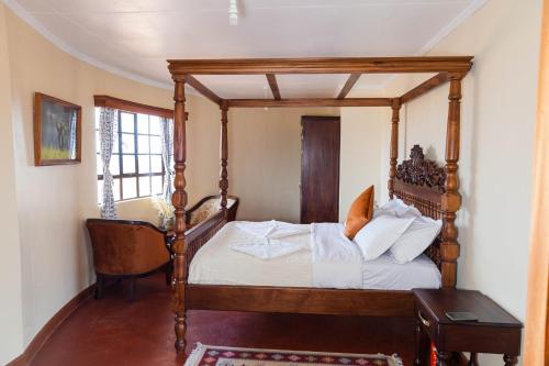 ein Schlafzimmer mit einem Himmelbett und einem Stuhl in der Unterkunft Wild Amboseli Ndovu Cottage. in Amboseli-Nationalpark