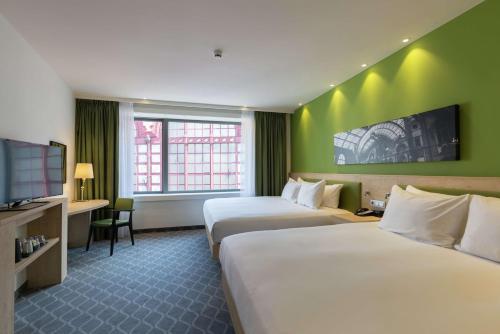 a hotel room with two beds and a flat screen tv at Hampton By Hilton Antwerp Central Station in Antwerp