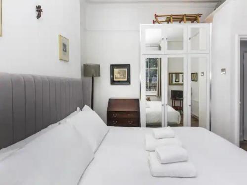 a white bedroom with a white bed and a mirror at Pass the Keys Lovely flat near Belsize Park, North Central London in London