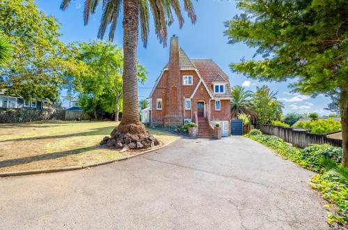 an old brick house with a palm tree in the driveway at Castle Charm with Modern Interiors, Steps to Shops in Auckland