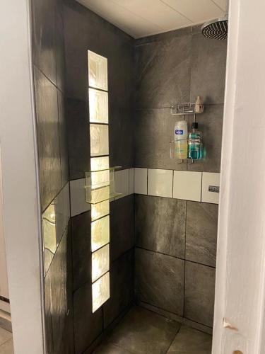une salle de bain avec une douche avec une porte vitrée dans l'établissement maison de village, à Ax-les-Thermes
