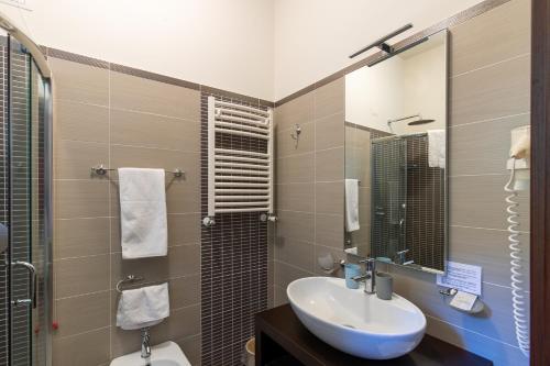 a bathroom with a sink and a toilet and a mirror at Villa Ginevra Resort Agrituristico in Ficarra