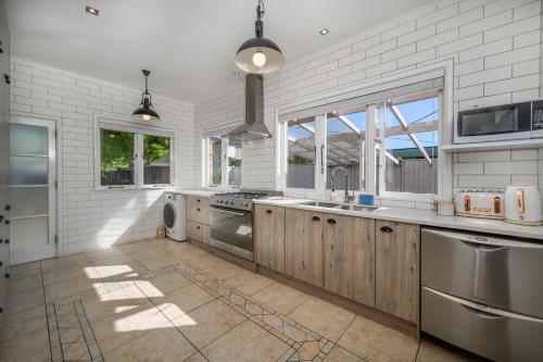 a large kitchen with white brick walls and wooden cabinets at Big Family House 9 BR 4BH 13 BED in Auckland