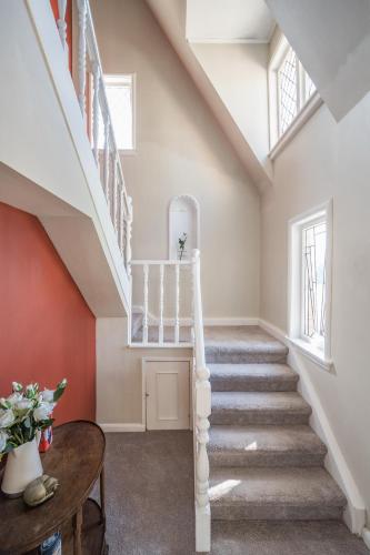 a staircase in a home with red walls and windows at Castle Charm with Modern Interiors, Steps to Shops in Auckland