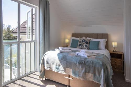 um quarto com uma cama e uma grande janela em Spring Lake 52, Eider Lodge - P em South Cerney