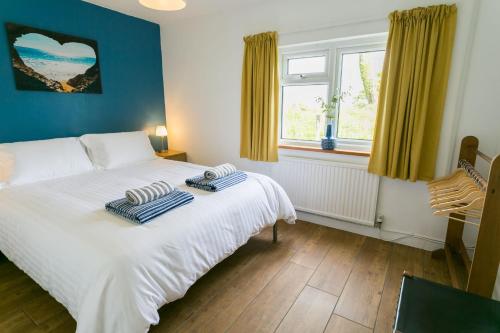 a bedroom with a white bed and a window at Cwter Hywel in Coedana