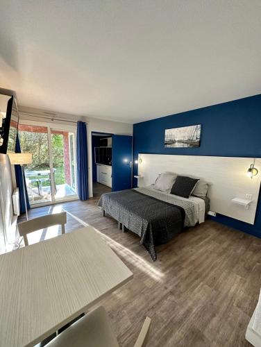 1 dormitorio con cama y pared azul en Joli studio Arles avec terrasse et verdure, en Arles