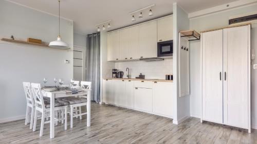 a kitchen and dining room with a table and chairs at Apartamenty Sun & Snow Jagiellońska in Darłowo