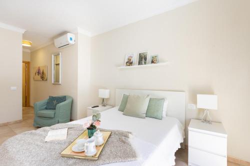 een witte slaapkamer met een bed en een blauwe stoel bij Villa Chloe Costa Adeje Tenerifesummervillas GIANT PRIVATE POOL 11 METERS LONG in Adeje
