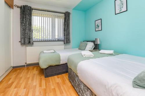 two beds in a room with blue walls and wooden floors at Peaceful Urban Getaway in Liverpool