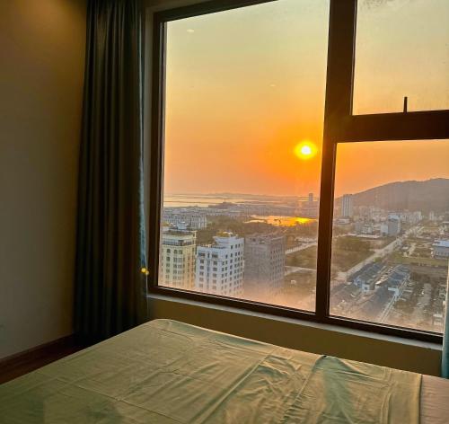 Dormitorio con ventana con vistas a la puesta de sol en By's House Căn hộ view vịnh Hạ Long en Ha Long