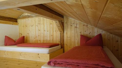 2 Betten in einem Zimmer mit Holzwänden in der Unterkunft Rossweid Huette in Stans