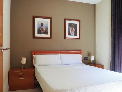 een slaapkamer met een bed met twee foto's aan de muur bij Tarragona Ciudad, El Serrallo AP-1 in Tarragona