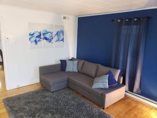 un soggiorno con divano e parete blu di Un appartement chaleureux décoré avec bon goût. a Saint-Jean-sur-Richelieu