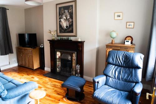a living room with blue chairs and a fireplace at Number 19 Heart Of The Glens in Cushendall