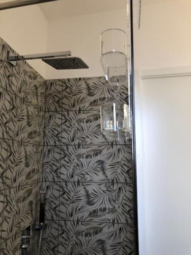 La salle de bains est pourvue d'une douche et de papier peint noir et blanc. dans l'établissement Attici Agli Acquedotti Romani, à Rome