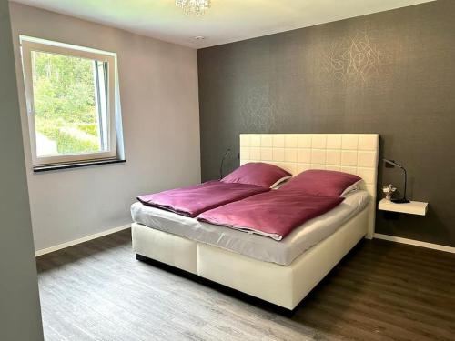 Un dormitorio con una cama con sábanas moradas y una ventana en Penthousewohnung direkt am Wald, en Nalbach