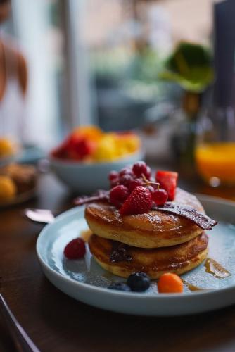 a plate of pancakes with fruit on a table at Grand Hotel Vilnius, Curio Collection by Hilton in Vilnius
