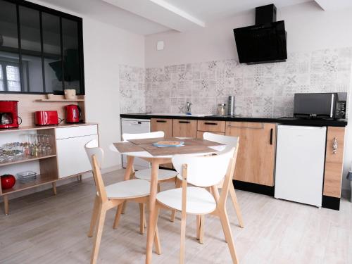 a kitchen with a wooden table and white chairs at Les Clématites de Saint-Aignan 4p, 7 min du Zoo in Saint-Aignan