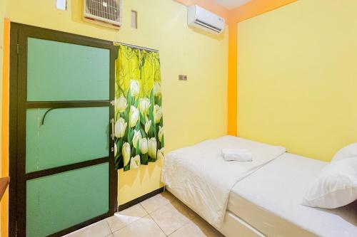 - une chambre avec 2 lits et une porte ornée de fleurs sur le mur dans l'établissement Sion Homestay Mitra RedDoorz near Terminal Kertajaya Mojokerto, 