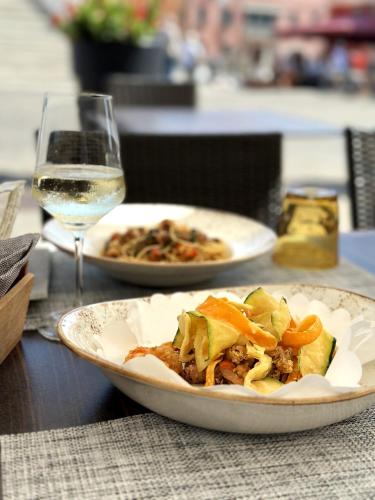 a table with two plates of food and a glass of wine at Hotel Grande Italia in Chioggia