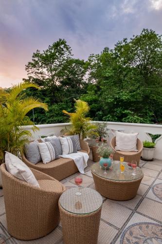 a patio with wicker chairs and tables and trees at LohonoStays Castello Villa 1 in Vagator