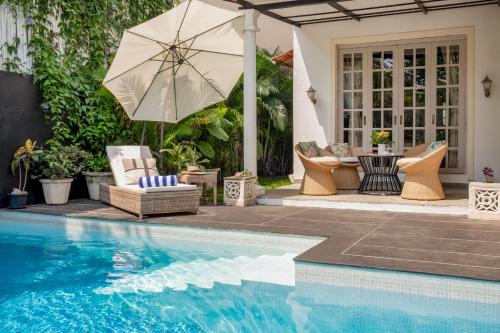 a pool with chairs and an umbrella next to a house at LohonoStays Castello Villa 1 in Vagator