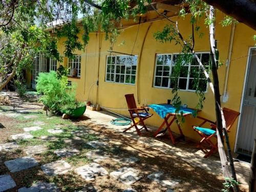 a patio with a table and chairs in front of a yellow house at Eins Art Studios in Omaruru