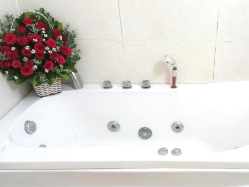 a white bath tub with a vase of red flowers at KHÁCH SẠN CÚC PHƯƠNG in Dĩ An