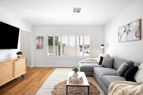a living room with a couch and a tv at Frankie's Retreat Henley Beach in Henley Beach