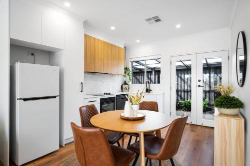 a kitchen with a table and chairs and a refrigerator at Frankie's Retreat Henley Beach in Henley Beach